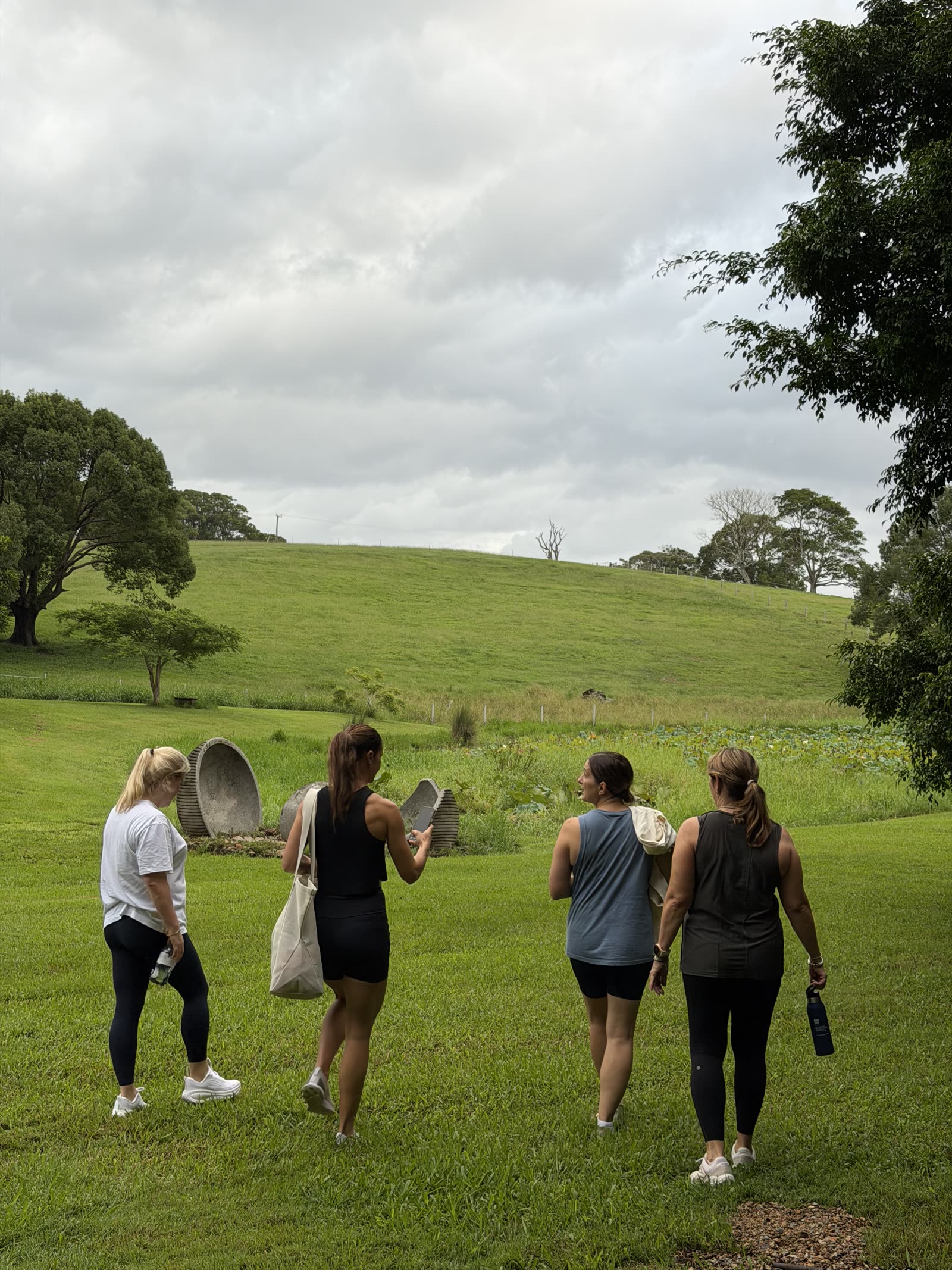 Four women walking across a green hillside
